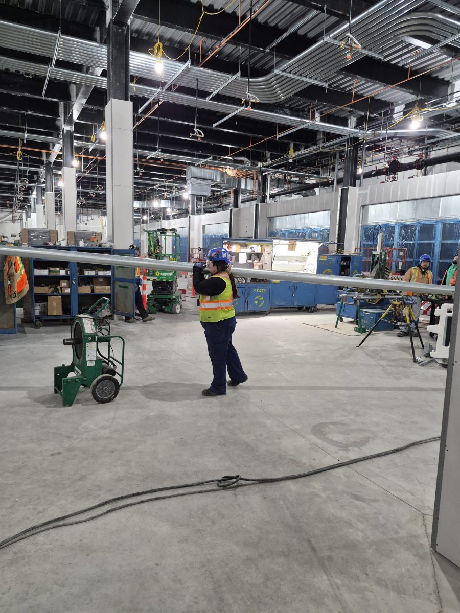 Kayla Chislett carrying a 20ft piece of 4 inch conduit by herself to where it needs to be installed.