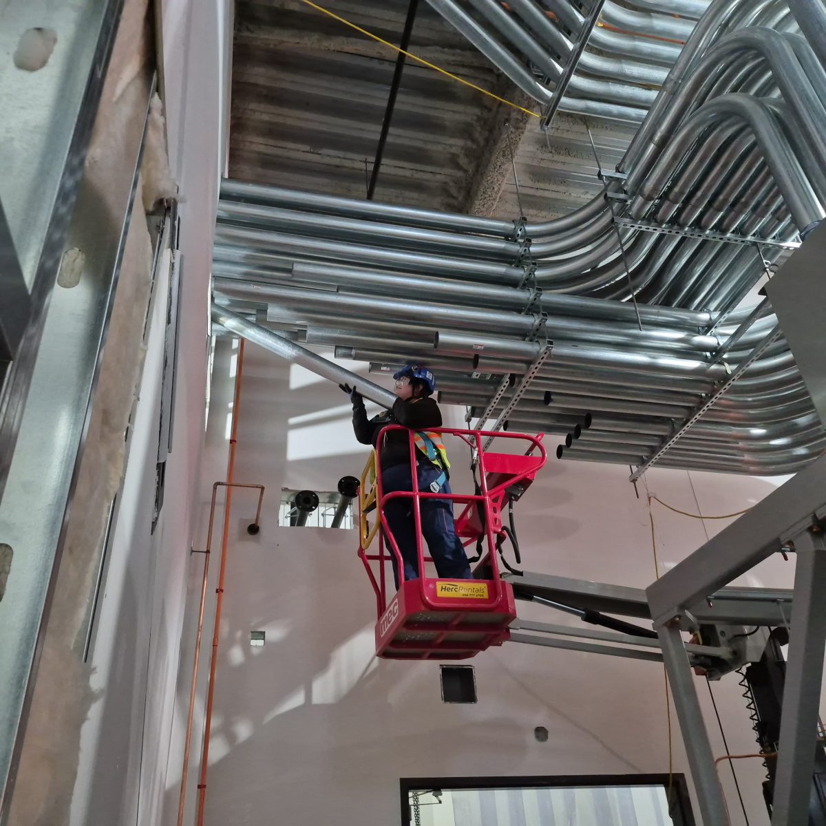 Kayla Chislett in the middle of working on multiple 4 inch conduit runs into a power distribution unit(PDU).